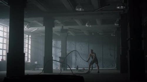 Wide Powerful Man Battling Ropes in Gym. Athletic Man Doing Fitness