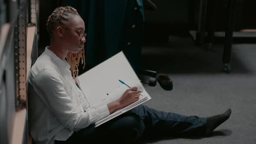 Young Adult Writing in Binder on Office Floor