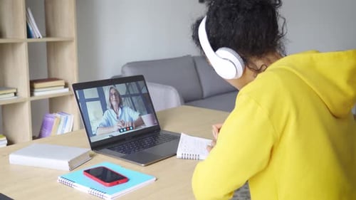 Woman in video call taking notes at home