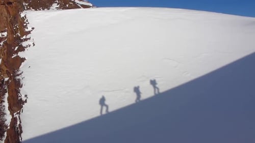 Bergsteiger befahren fachmännisch einen verschneiten, zerklüfteten Gipfel und stellen dabei ihr Können und ihre Entschlossenheit unter Beweis