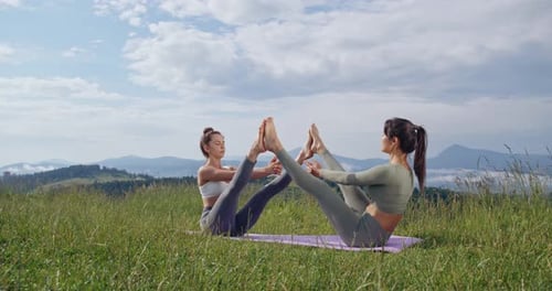Two Women Practicing Yoga Outdoors in Mountains