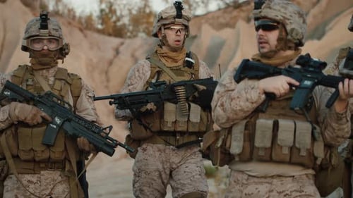 Gruppe voll ausgerüsteter und bewaffneter Soldaten, die in der Wüstenumgebung auf die Kamera zugehen.