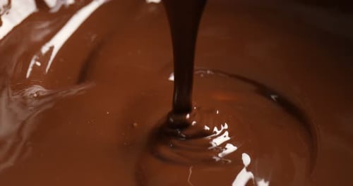 Tasty melted chocolate flowing down from spoon, closeup