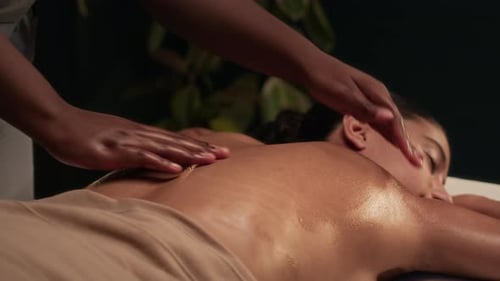 Close-up of Hands of Unknown Masseuse Rubbing Essential Oil over Clients Back