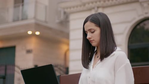Woman Working on Laptop in Urban Setting