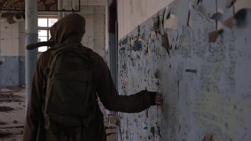 Ein Stalker mit Gasmaske geht durch ein altes zerstörtes Gebäude