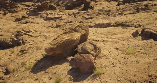 Rocky Terrain with Scattered Boulders Under Bright Sunlight in a Dry Landscape