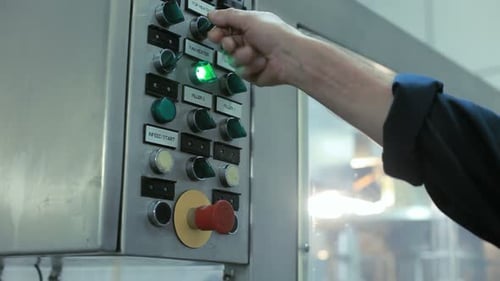 Un trabajador ajusta con precisión el panel de control automatizado a mano en una moderna fábrica industrial