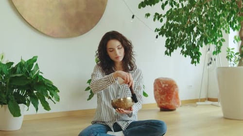 Woman Playing Singing Bowl for Meditation at Home