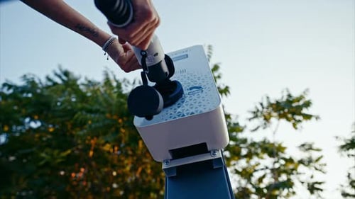 Charging electric car. A woman charging her environmentally-friendly electric car on the parking lot