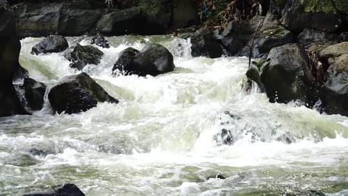 Water river courses through the rock. Clear water stream glides over rocks. Close up shot of rapids