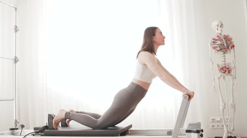 Woman Doing Pilates Exercise on Reformer Machine