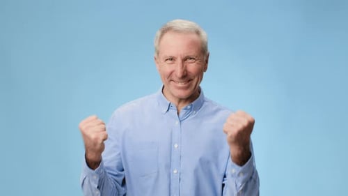 Smiling Man Shows Excitement With Clenched Fists Against a Light Blue Background in a Video