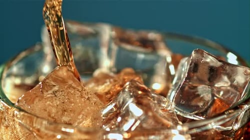 Soda Pouring Over Ice in Glass, Close Up