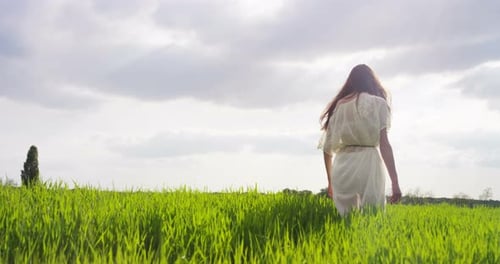 Woman Walking Through Tall Grass in Meadow
