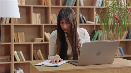 Woman works with laptop and papers in office