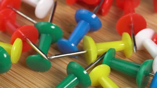 Colorful push pins rotating on the table macro. Drawing pins for marking on the map of the Earth
