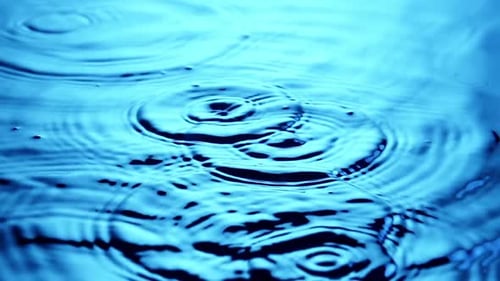 Water Droplets Create Ripples in Blue Water