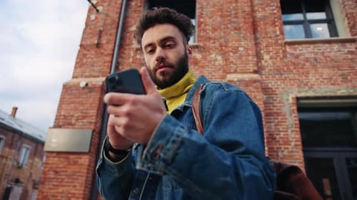 Man Using Smartphone Outside Brick Building