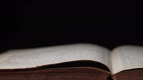Side View of Old Open Book on Table in Library Worn Pages Slider Ancient Writings on Black