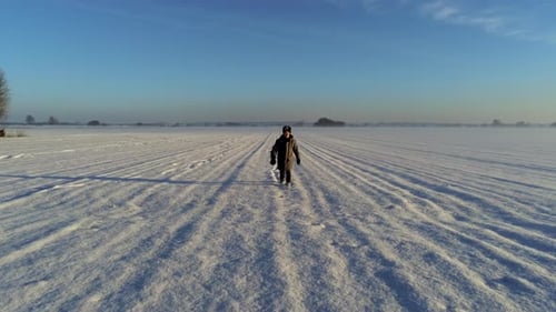 Dolly shot of little boy walking on field full of snow