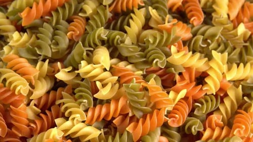 Pâtes italiennes multicolores Fusilli ou Rotini tombant en arrière-plan, vue latérale en gros plan. blé dur