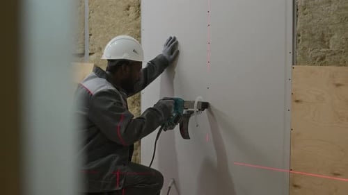 Construction Worker Drilling Drywall Using Laser Guide