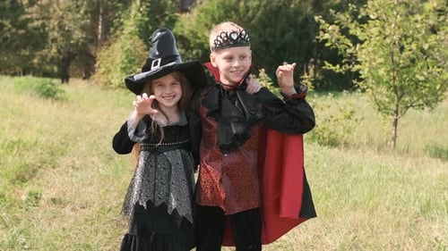 Children Boy and Girl in Carnival Costumes of Witches and Dracula on the Street are Enjoying the