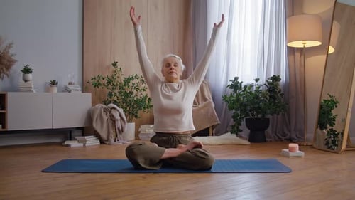 Mature Woman Meditating on Yoga Mat at Home
