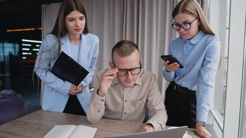 Male manager looking at laptop in surprise, putting off his glasses.