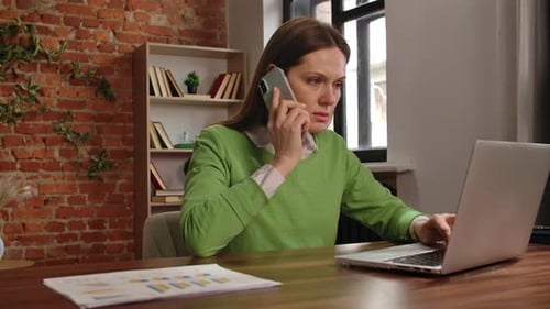 Woman Works on Laptop and Talks on Phone