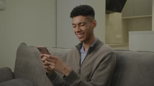 African American Man Texting Using Mobile Phone 20s Male is Addicted to Smartphone Sitting at Home