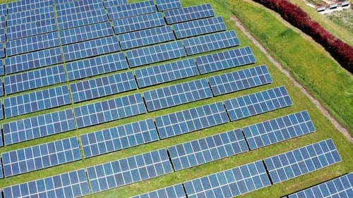 A large solar panel farm on a sunny day, aerial view