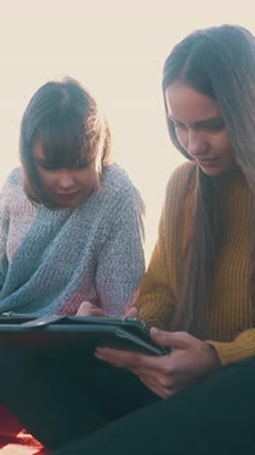 Two Young Women Looking at Tablet Outdoors