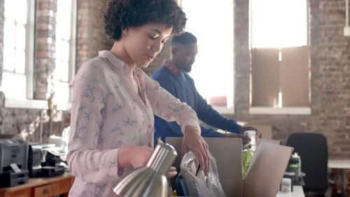 Diverse colleagues unpacking boxes with documents and office items in creative office in slow motion