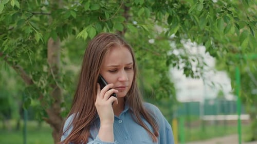 Upset Woman Talking on Phone in Park
