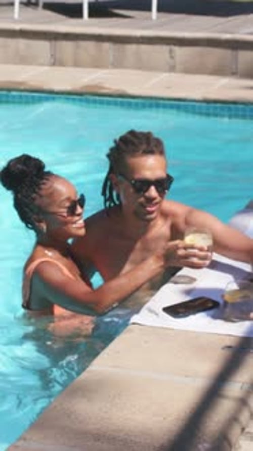 Vertical video: Spotting drinks, shirtless man and orange-swimsuit woman toasting at home pool