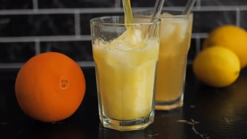 Pouring Fresh Orange Juice Into Glass with Ice
