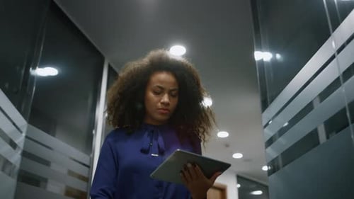 African american business woman walking office corridor using tablet for data