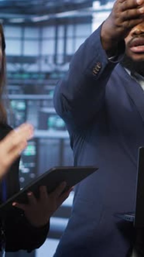 Vertical Video Coworkers in Server Room Optimizing Data Center Tech with Laptop and Tablet
