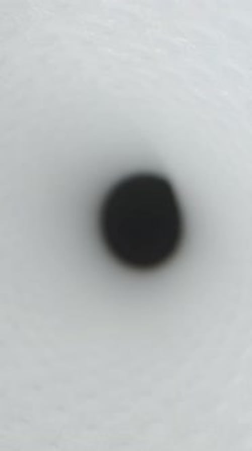 Vertical video. The camera moves inside a white tunnel towards darkness. Dolly slider macro