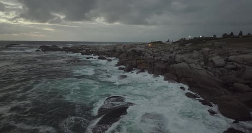 Drone flying backwards above the ocean at Camps Bay beach in Cape Town South Africa - It's a cloudy