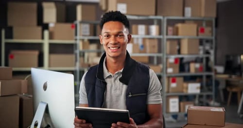 Smiling Young Adult Holding Tablet in Warehouse