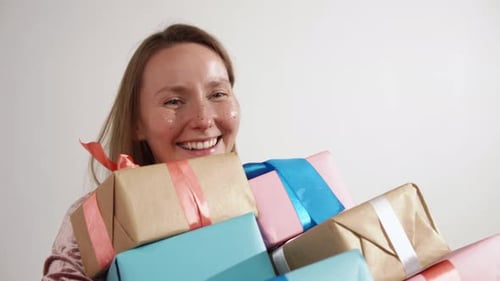 Woman Smiling While Holding Colorful Stack of Wrapped Gifts