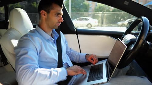 Handsome Entrepreneur Working on Notebook While Riding an Autonomous Self Driving Electric Car at