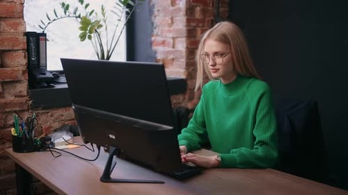 Junge Frau arbeitet im modernen Büro und tippt Text auf der Tastatur einer Laptop-Programmiererin