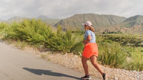 Curvy Girl Runs on a Mountain Road Pushing Through Fatigue for Better Fitness