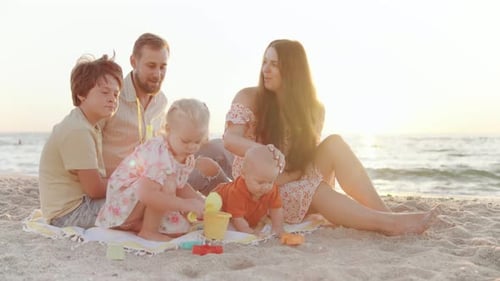 A Family Spends a Joyful Day at the Beach As Their Kids Play with Colorful Toys on the Sand with the