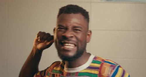 Close Up Of Afro American Man Wearing Kente Fabric Shirt Excitingly Celebrating In Slow Motion