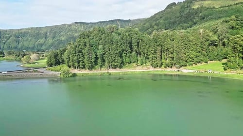 Beautiful lake surrounded by lush green forest and mountains under a bright sky